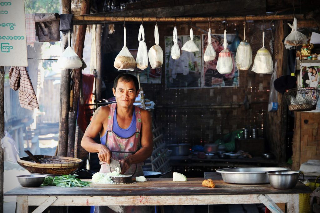 Foto tomada en Tailandia. Un nativo cocina en lo que parece un puesto de comida callejero.