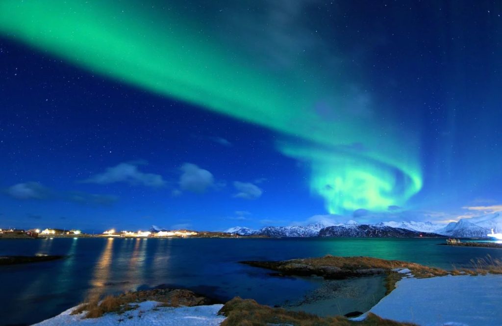 La aurora voreal luce junto a un fiordo noruego. ¿Qué documento necesito para viajar a Noruega?