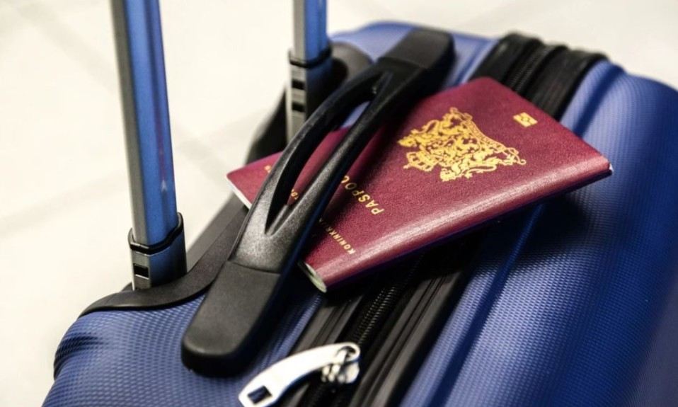 Un pasaporte posa sobre una maleta de viaje de colores azul y negro.