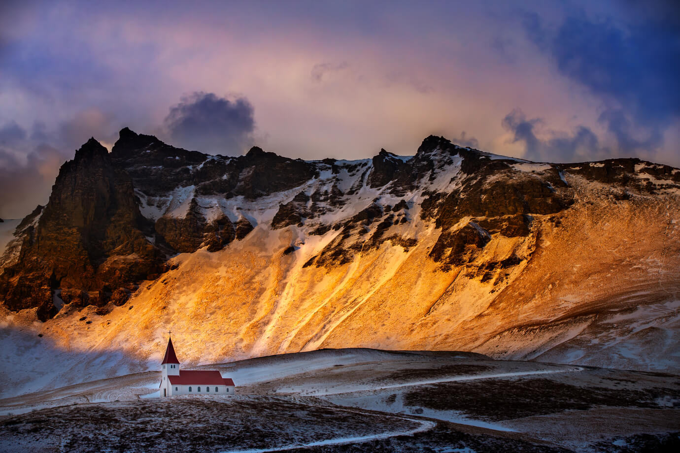 Iceland, beautiful sunset landscape of Vik Myrdal village, kurkirka church against the snowy mountains, South coast of Iceland