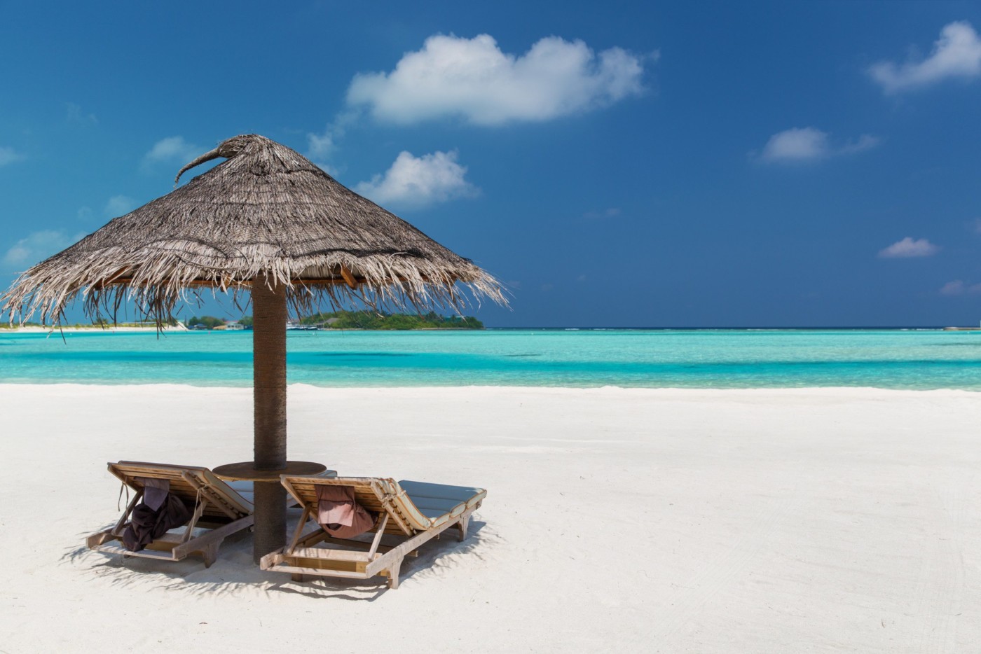 travel, tourism, vacation and summer holidays concept - palapa and sunbeds over sea and sky on maldives beach